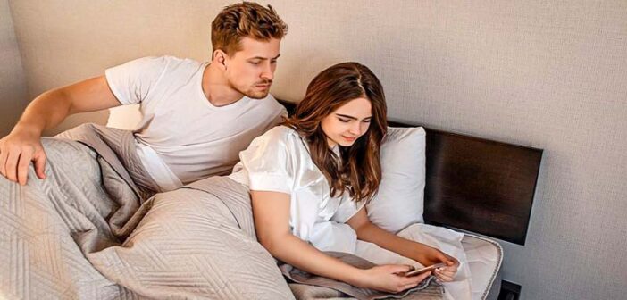 Le petit ami regarde les messages texte de sa petite amie par-dessus son épaule - illustration d'un partenaire qui a des problèmes de confiance.