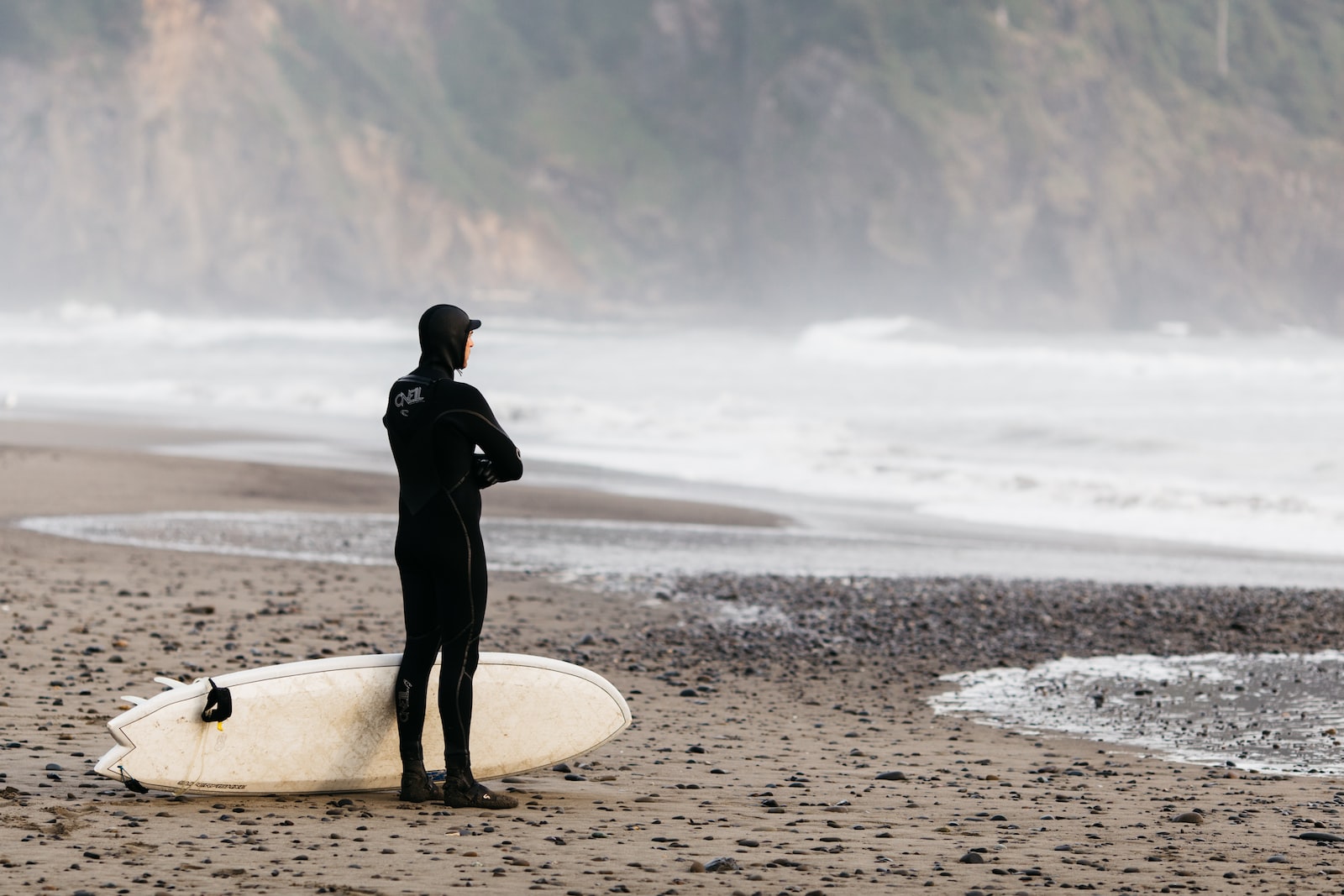 homme debout sur le rivage avec une planche de surf