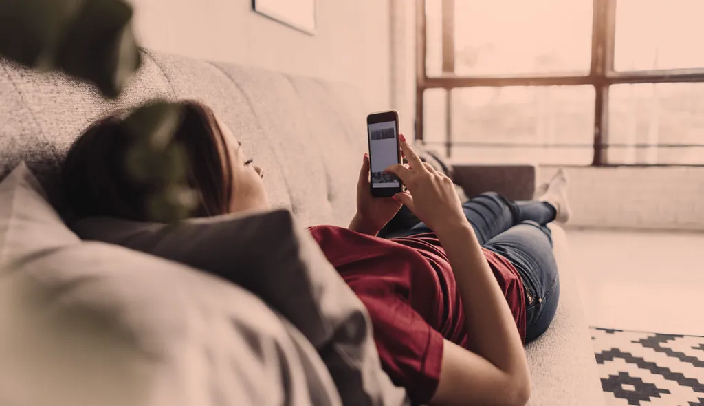 A woman sitting on a sofa looking at her phone