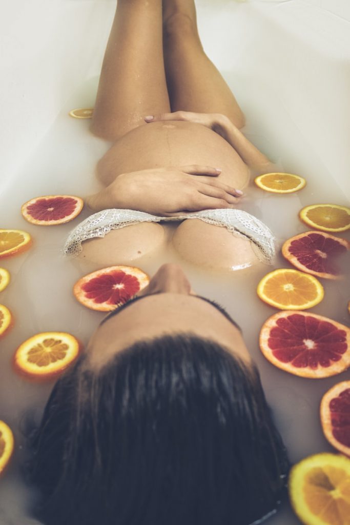femme dans une baignoire en céramique blanche avec des tranches d'orange