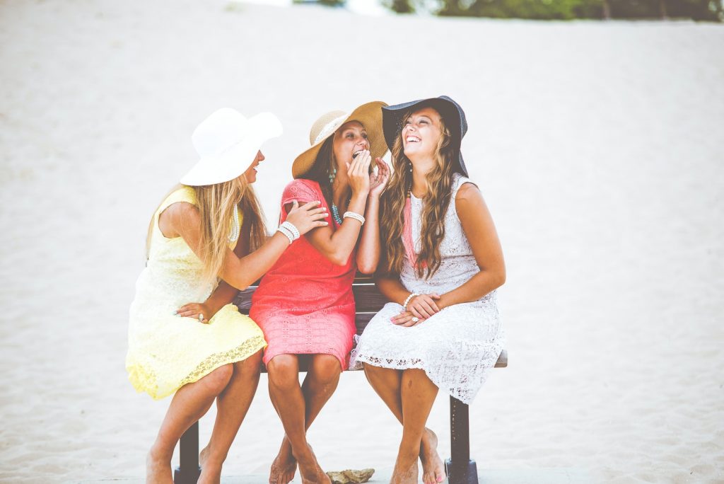 trois femmes assises sur un banc en bois brun