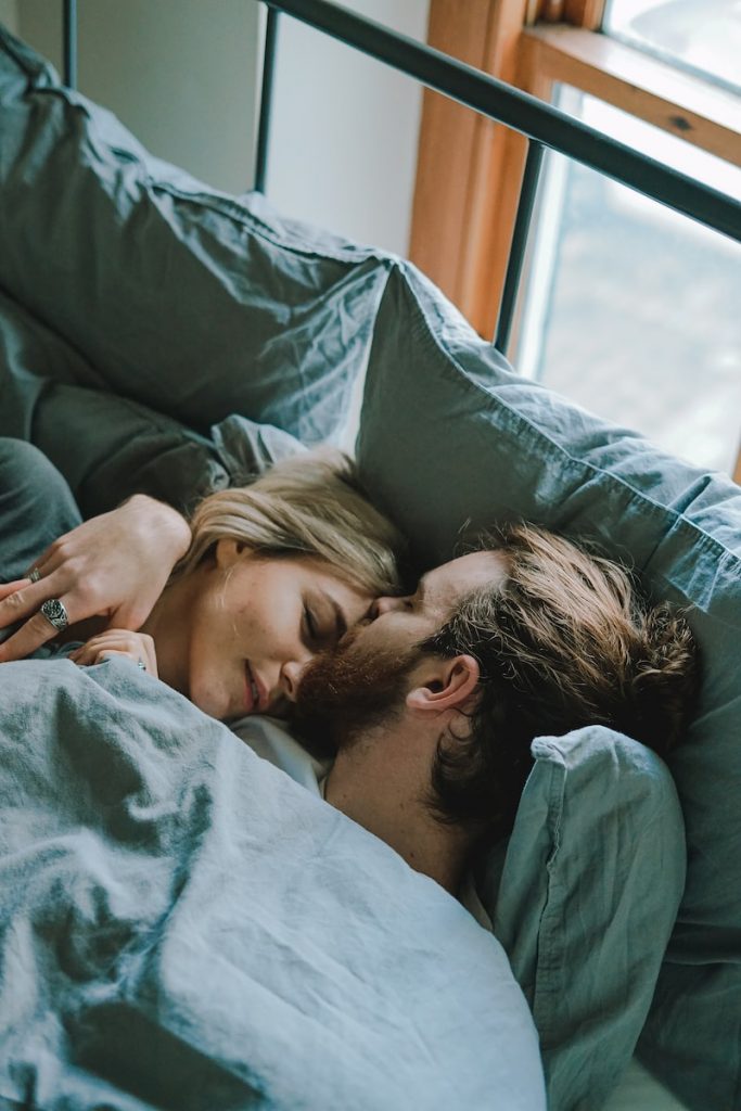 homme embrassant le front d'une femme allongée sur un lit