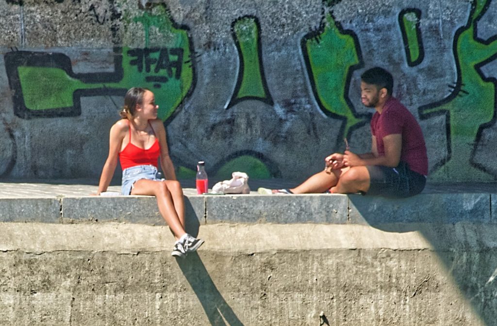femme en bikini rouge assise sur un banc en béton au bord d'une piscine pendant la journée