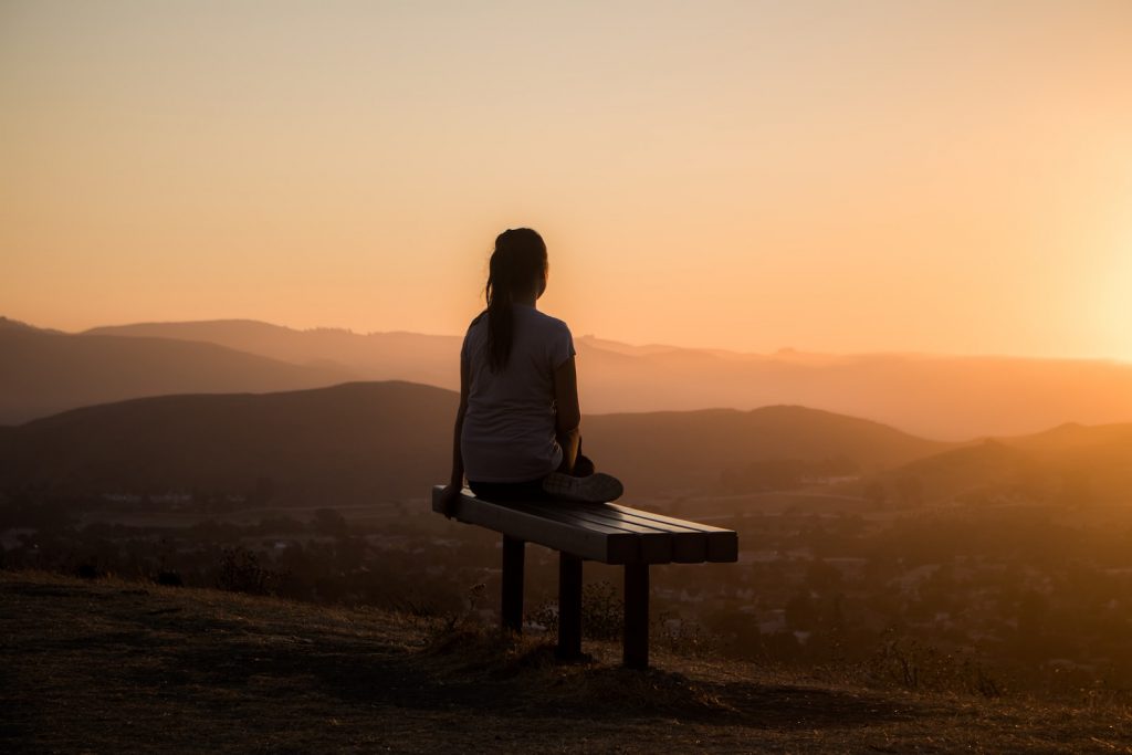 femme assise sur un banc avec vue sur la montagne