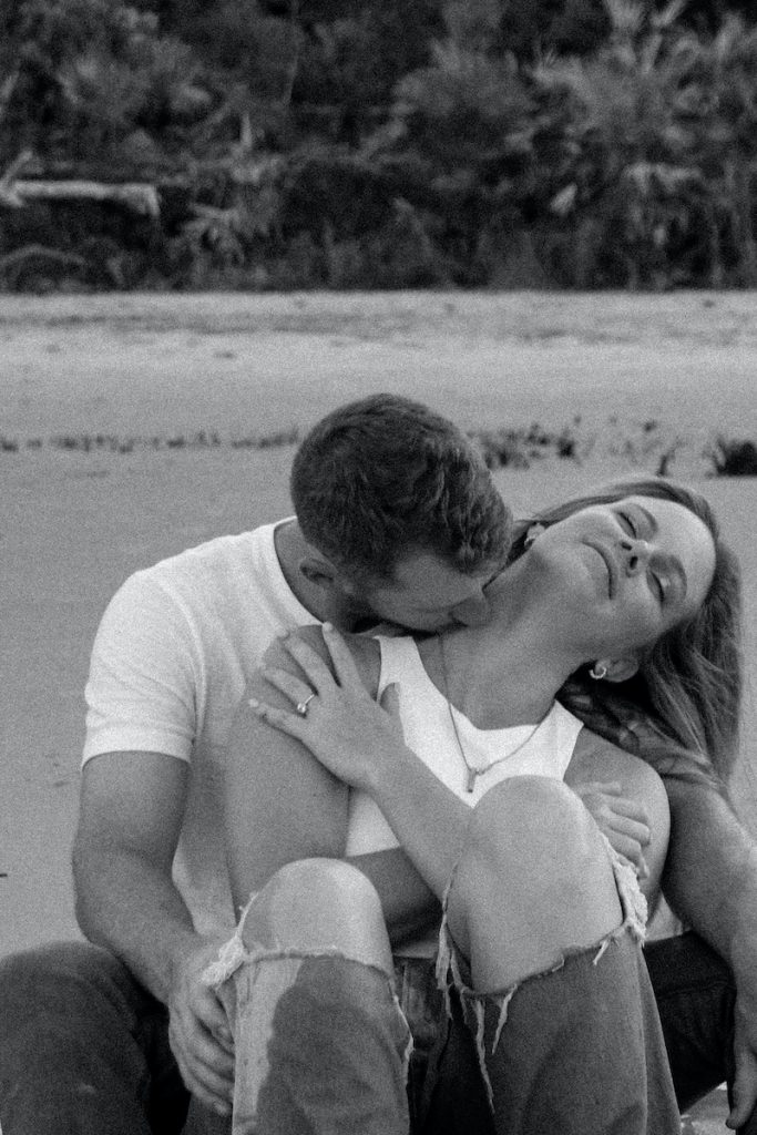Homme en T-shirt blanc embrassant une femme en débardeur blanc sur la plage
