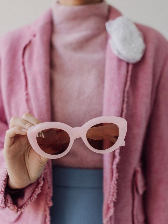 femme tenant des lunettes de soleil roses