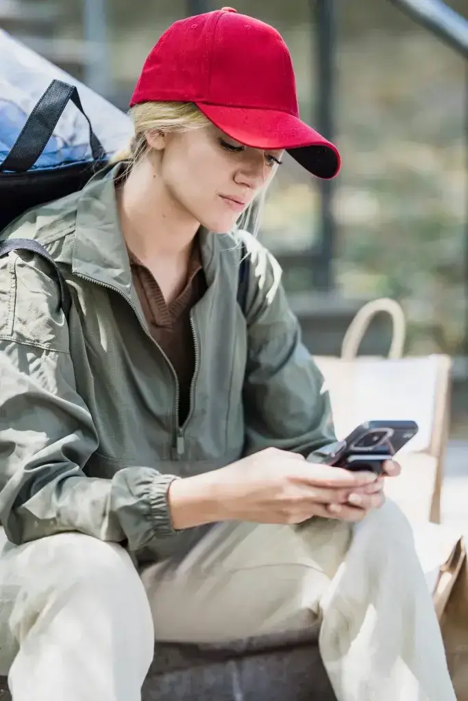 Une femme habillée avec désinvolture en public et regardant son téléphone.